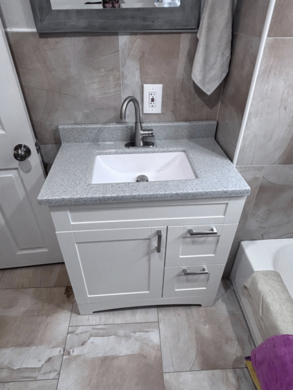 Bathroom vanity detail with white cabinet and stone top